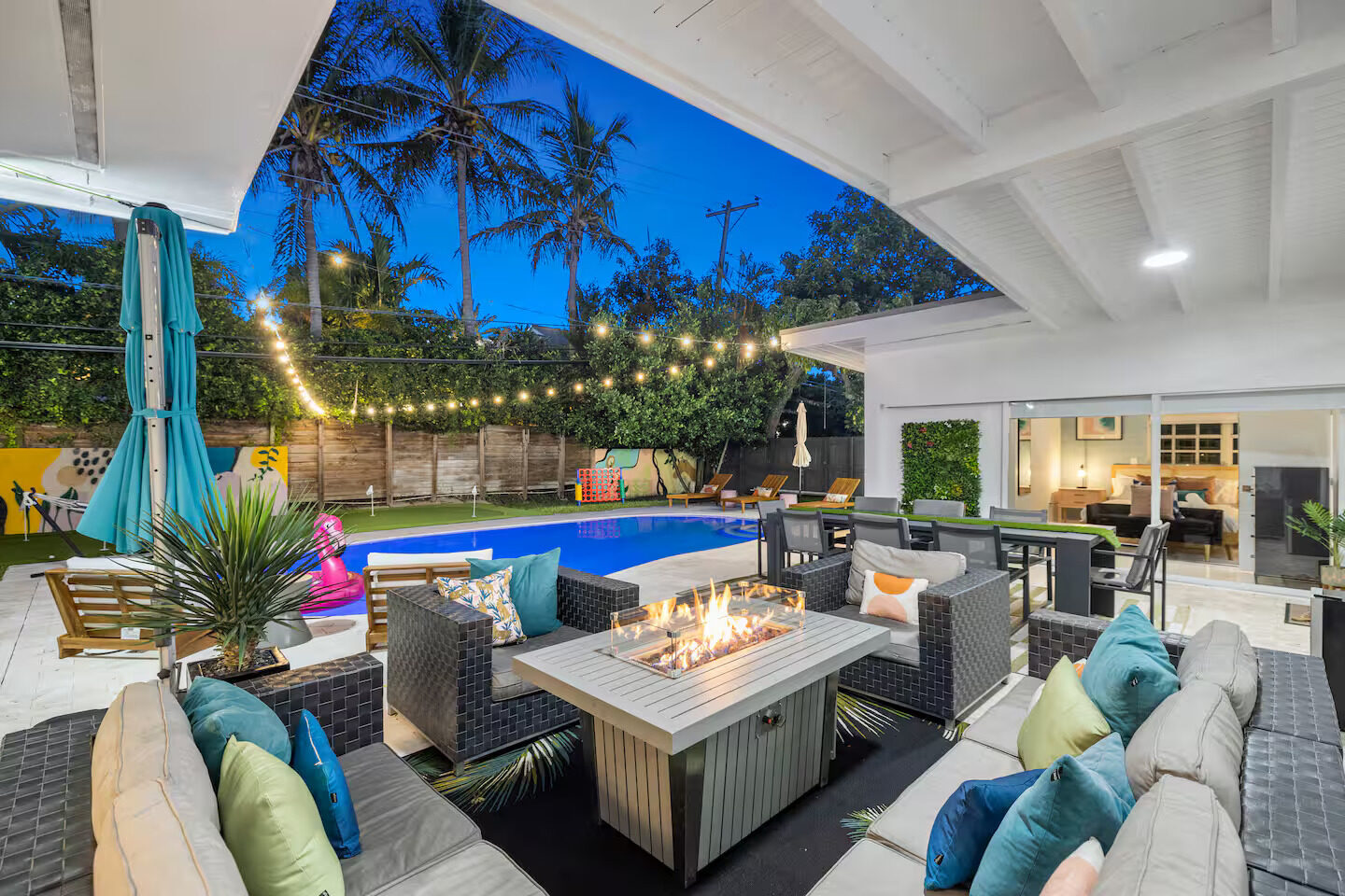 Backyard pool with fire pit and string lights at twilight
